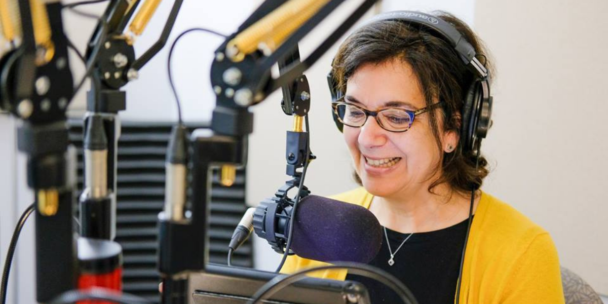 Aux quotidiens. Photo d'Hélène Denis, en studio derrière le micro, lisant l'actualité en ondes.