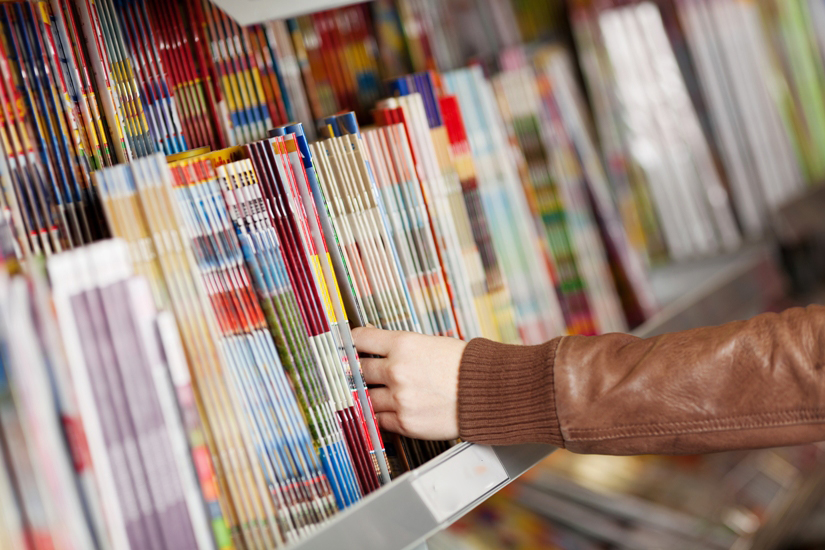 Une main prenant un magazine dans un kiosque
